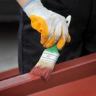 Малярные работы (шагрень) Worker painting steel tube with paint brush focus on hand
